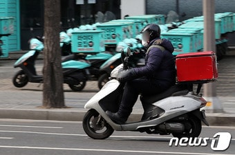서울 강남구 배민라이더스 남부센터에 배달용 오토바이 앞으로 한 배달 노동자가 지나가고 있다. ⓒ News1 박세연 기자