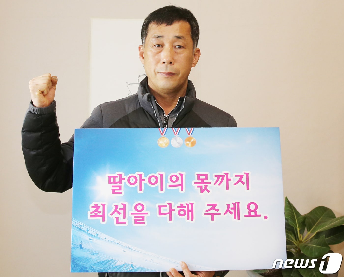 고 최숙현 선수의 부친 최영희씨가 베이징올림픽에 출전한 대한민국 대표팀을 응원하는 피켓을 들고 사진을 찍고 있다. (칠곡군 제공) 2022.2.6/ⓒ 뉴스1