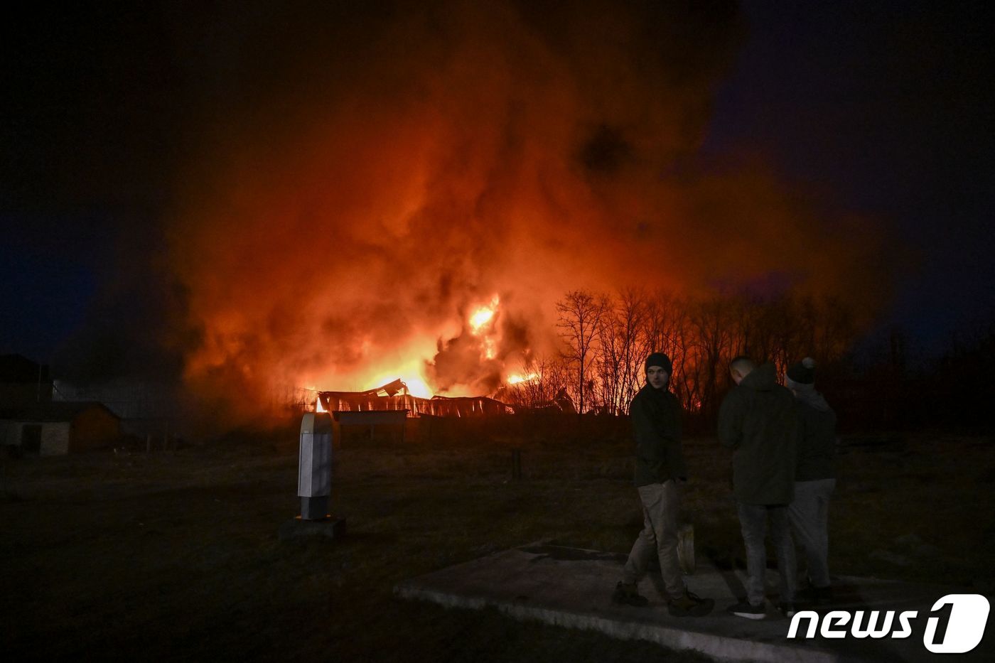 17일 키이우에서 러시아 군의 포격을 받아 불 타는 창고 앞에 우크라이나 군이 서 있다. ⓒ AFP=뉴스1 ⓒ News1 우동명 기자