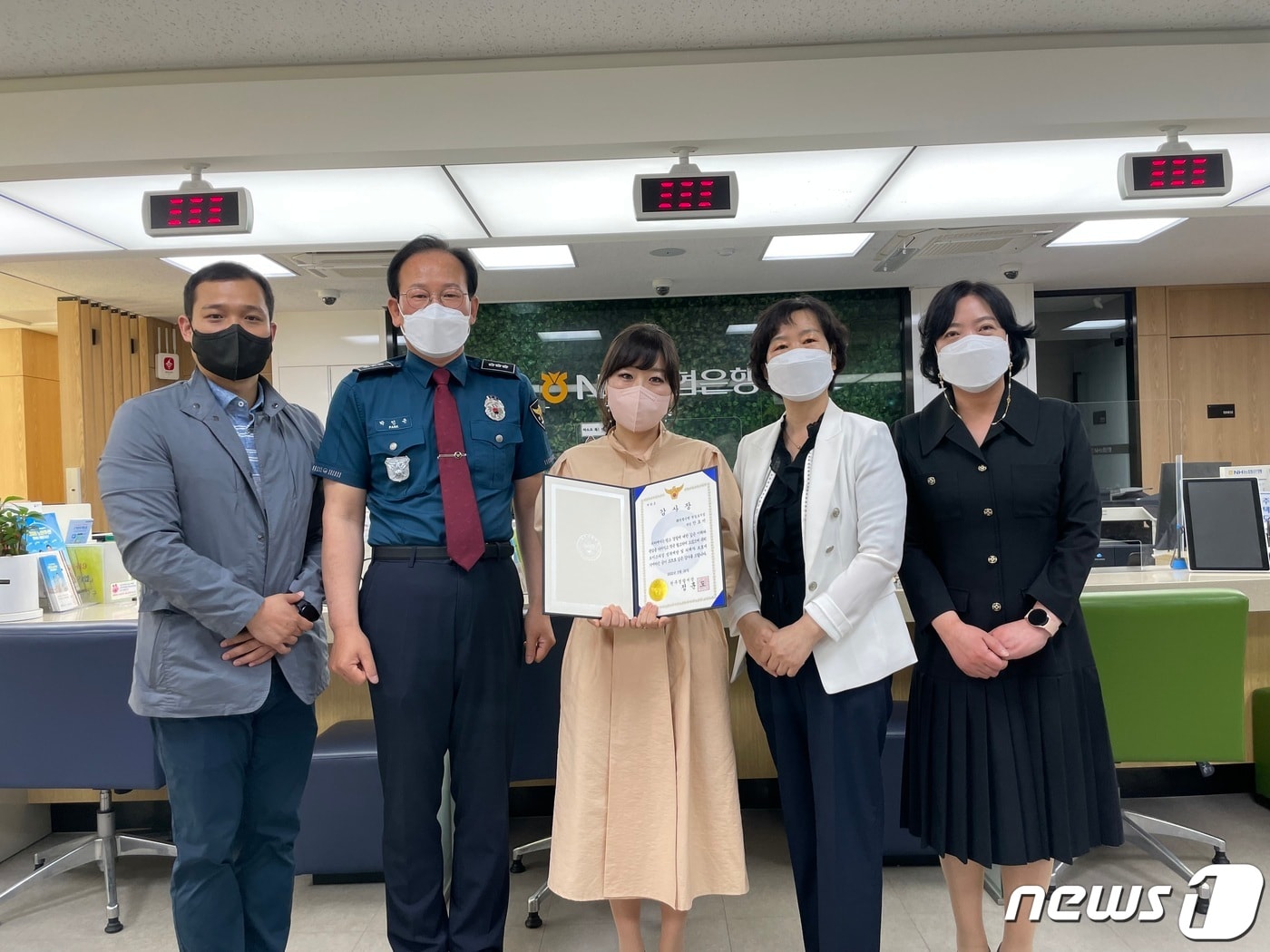 강원 원주경찰서가 26일 NH농협은행 원주 원일로지점에서 최근 보이스피싱 피해를 예방한 안효미 원일로지점 계장(가운데)에게 감사장을 전달한 가운데 관계자들이 함께 기념사진을 촬영하고 있다. (원주경찰서 제공) 2022.5.26/뉴스1
