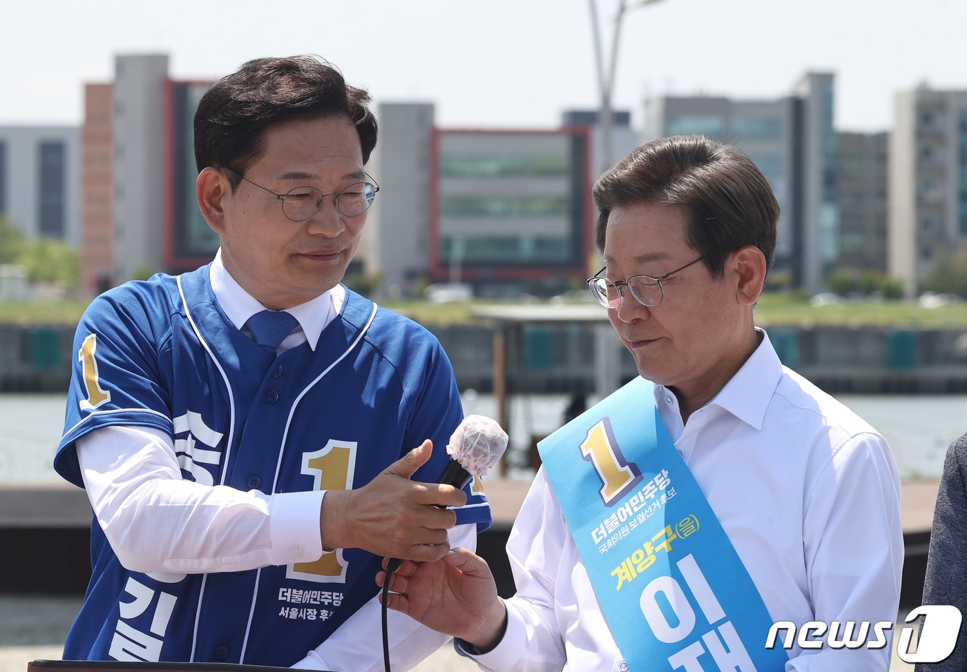 2022년 5월 27일 송영길 더불어민주당 서울시장 후보가 김포시 고촌읍 아라 김포여객터미널 아라마린센터 앞 수변광장에서 열린 김포공항 이전 수도권 서부 대개발 정책협약 기자회견에서 이재명 인천 계양을 국회의원 후보에게 마이크를 넘기고 있다. 2022.5.27 ⓒ 뉴스1 국회사진취재단