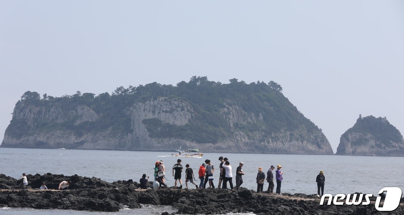 제주 서귀포시 법환동에서 관광객들이 해안가를 거닐고 있다. 뒤로는 멀리서 보면 호랑이가 웅크리고 있는 것 처럼 보인다는 범섬이 보인다.ⓒ News1 고동명 기자
