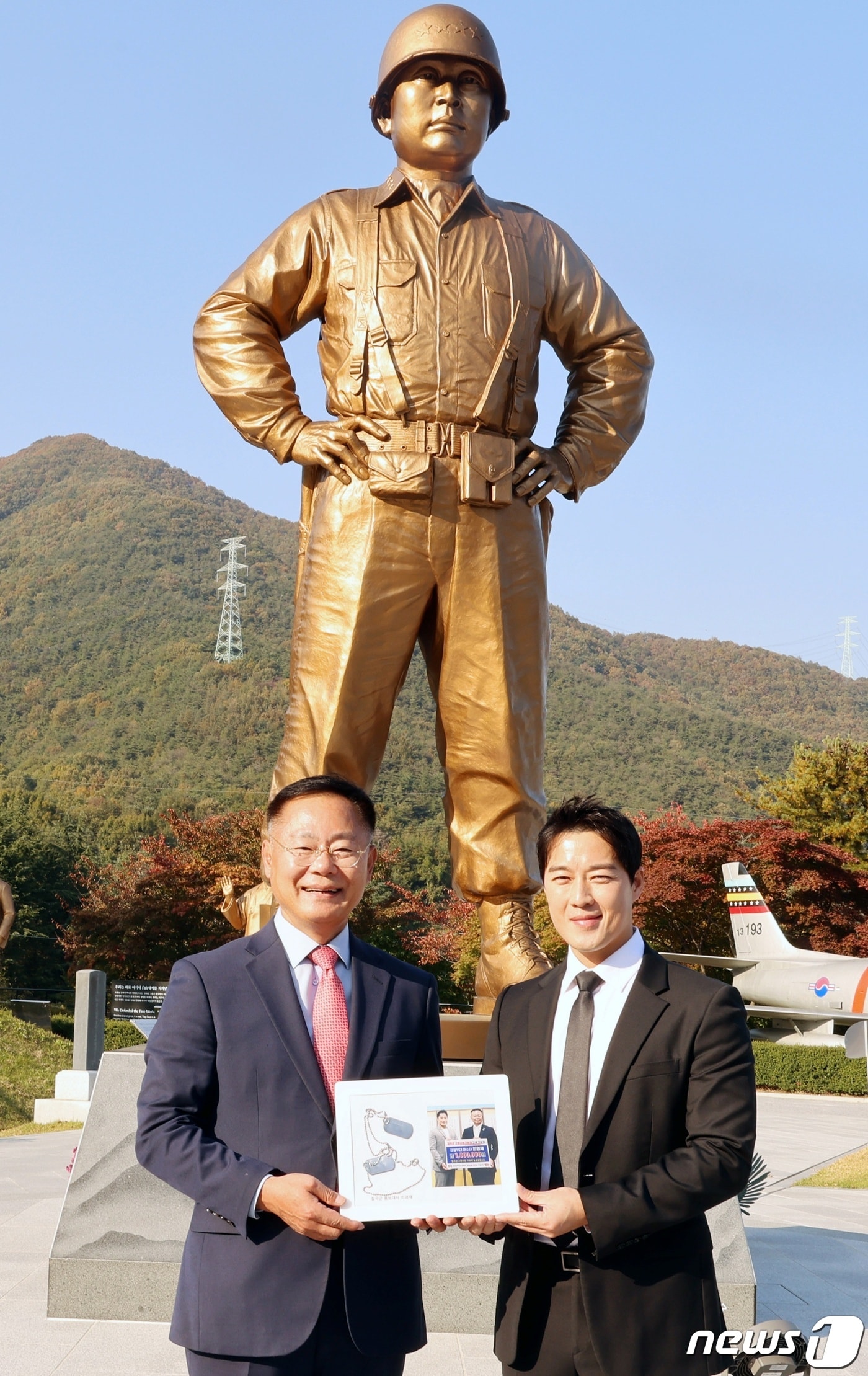 백선엽 장군 동상 앞에서 최영재 마스터가 29일 군번줄로 만든 액자를 김재욱 칠곡군수에게 전달하고 기념촬영을 하고 있다.(칠곡군 제공) 2023.10.30/뉴스1
