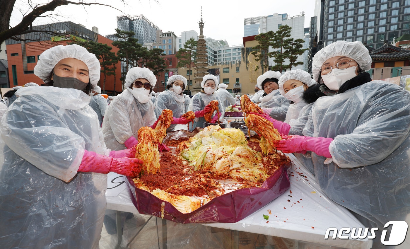 29일 오전 서울 종로구 조계사 대웅전 앞마당에서 열린 이웃과 함께 따뜻한 조계사 김장 나눔전에서 신도들이 김치를 들어보이고 있다. 2023.11.29/뉴스1 ⓒ News1 김민지 기자