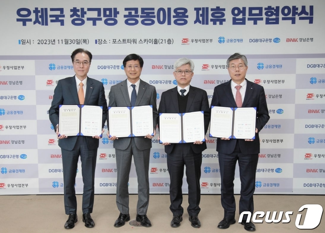 30일 황병우 DGB대구은행장(오른쪽)이 조해근 우정사업본부장(오른쪽 두번째)과 '우체국 창구망 공동이용 제휴 업무협약'을 체결한 뒤 협약서를 펼쳐 보이고 있다.(대구은행 제공)