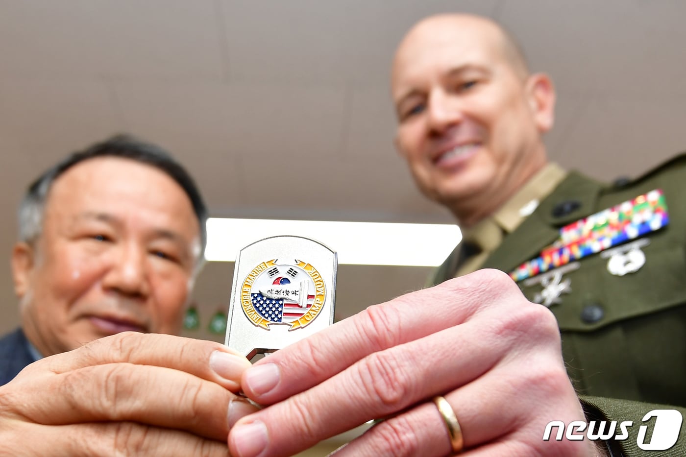 로니 D.마이클 캠프무적 부대장(대령)이 경북 포항시 선린애육원에서 열린 벽화 제막식에서 박정민 선린애육원장에게 부대상징 코인을 선물하고 있다. 캠프무적 해병과 군무원 등 20여명은 지난달 10월 6일부터 2개월 간 휴일을 이용 약 100m벽에 만화 캐릭터 벽화를 그렸다.2023.12.21/뉴스1 ⓒ News1 최창호 기자