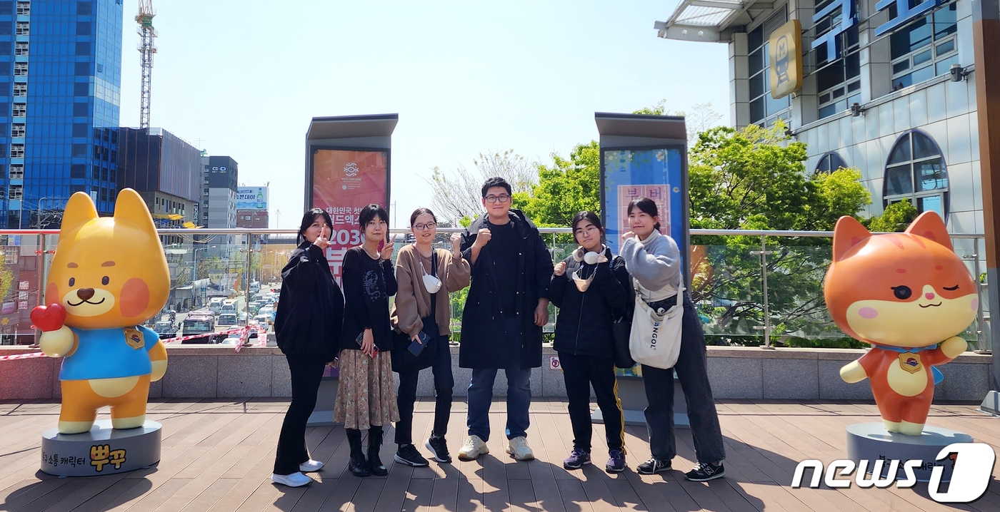 이승희 동서대학교 웹툰학과 교수(가운데)와 학생들이 부산 지하철 구포역 광장 ‘뿌꾸와 꾸미’ 포토존에서 기념 사진을 찍고 있다.(동서대 제공)