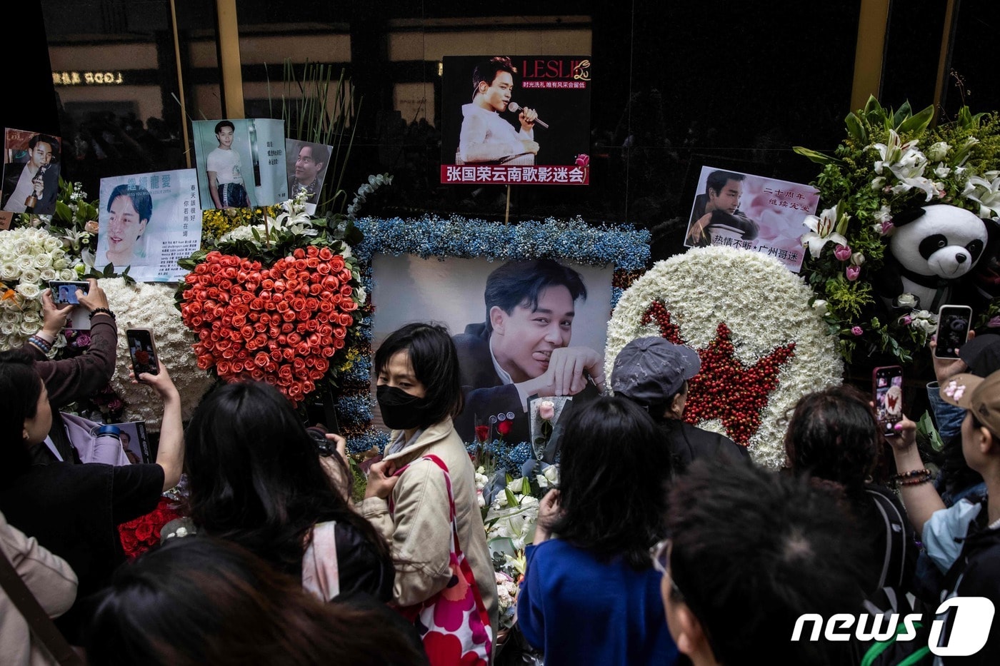 홍콩의 가수 겸 배우였던 장국영의 사망 20주기를 맞은 1일(현지시간) 홍콩에서 시민들이 길가에 놓인 추모 화환과 그의 생전 모습을 카메라에 담고 있다. 2023.04.01. ⓒ AFP=뉴스1 ⓒ News1 김성식 기자