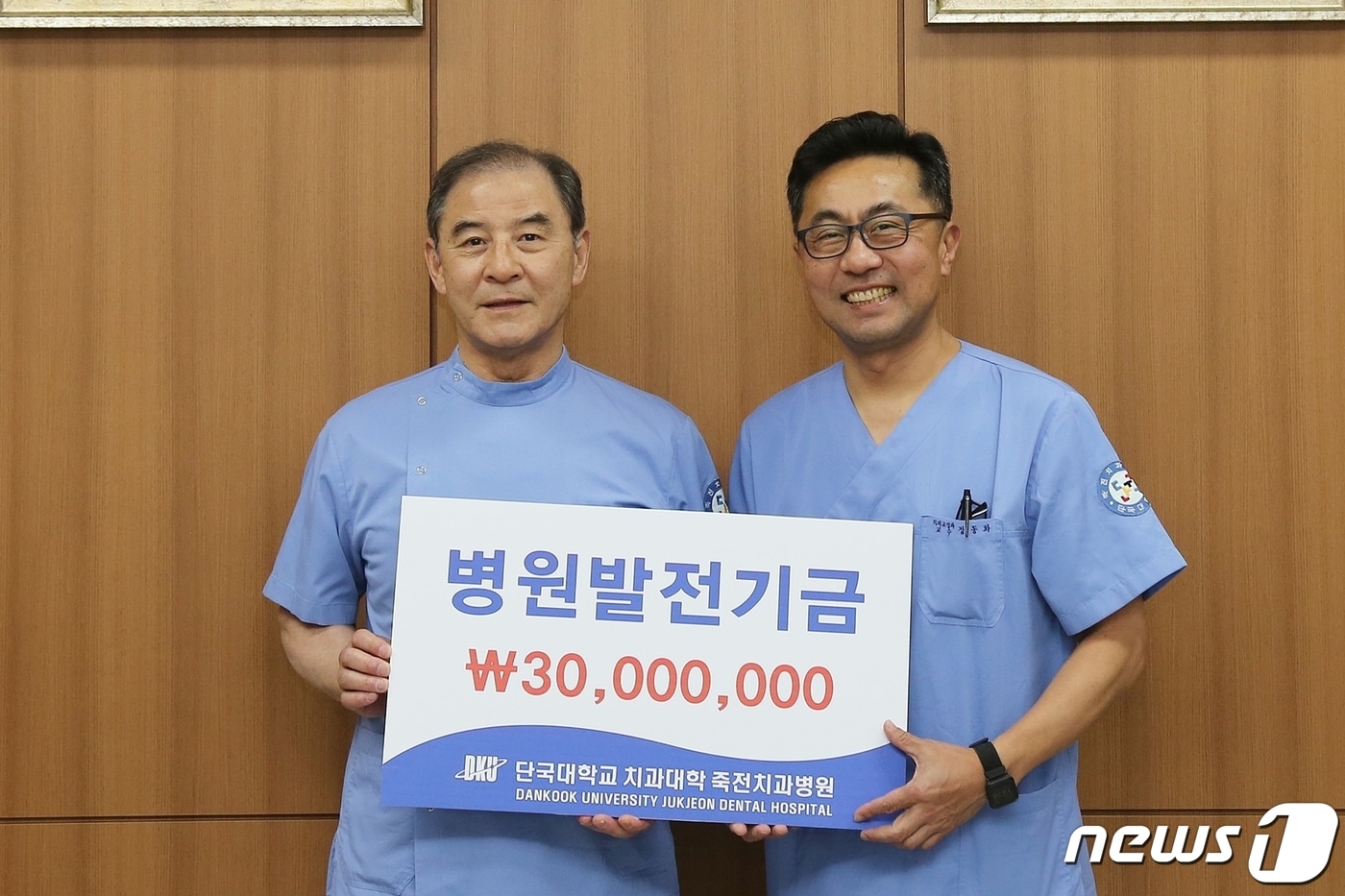 홍찬의 석좌교수(왼쪽)가 정동화 단국대 죽전치과병원장에게 발전기금을 전달하고 있다.(단국대 제공)