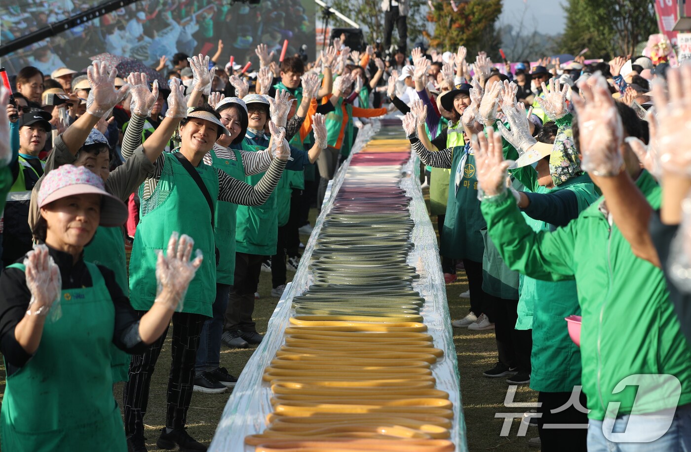 ‘제23회 이천쌀문화축제’가 개막한 16일 오후 경기 이천시 모가면 이천농업테마공원에서 행사 관계자들이 600m 가래떡을 만들고 기념촬영을 하고 있다. 2024.10.16/뉴스1 ⓒ News1 김영운 기자