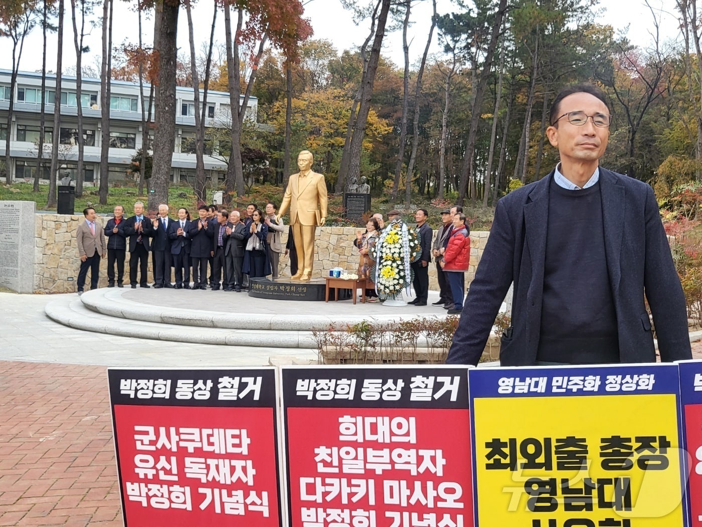 14일 오전 영남대 민주동문회 회원이 영남대에 건립된 박정희 전 대통령 동상 앞에서 철거를 요구하는 1인 시위를 하고 있는 가운데 총동창회 회원들이 박 전 대통령 탄신 107돌을 기념하며 동상 앞에서 단체 사진을 촬영하고 있다.2024.11.14/뉴스1 ⓒ News1 이성덕 기자