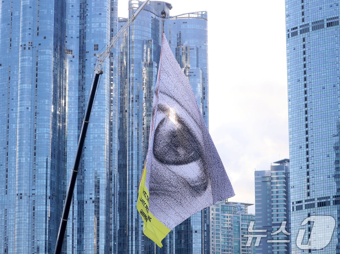 25일 오전 국제 플라스틱 협약 제5차 협상회의(INC5)를 앞두고 국제 환경보호 단체인 그린피스가 부산 해운대구 수영만요트경기장 내 건물 10층 높이의 크레인에 가로 30m, 세로 24m 크기의 초대형 눈 형상 깃발을 설치해 퍼포먼스를 벌이고 있다. ⓒ News1 윤일지 기자