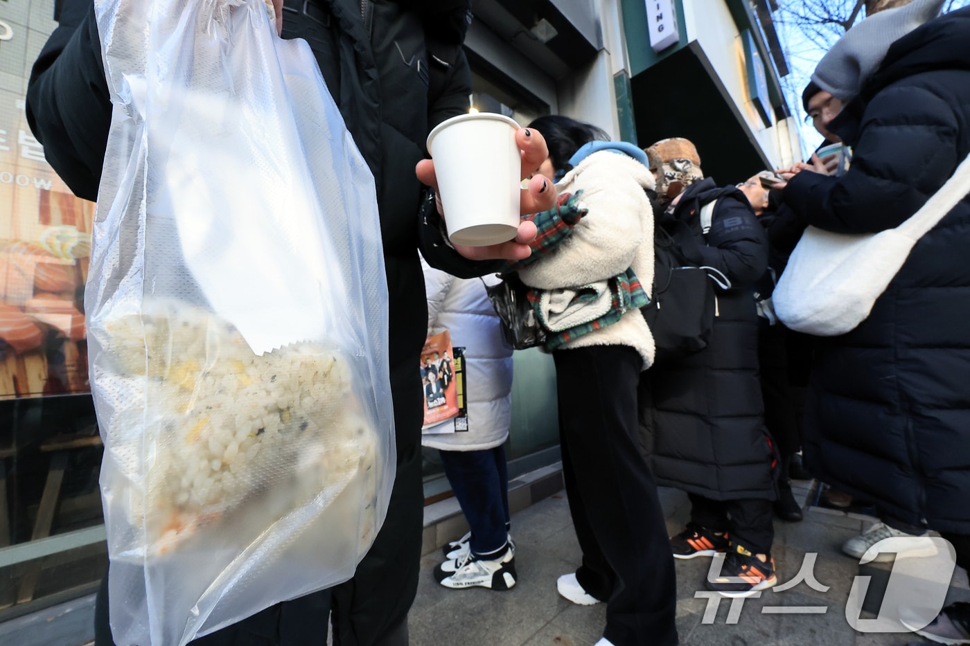 윤석열 대통령에 대한 탄핵소추안 표결이 예정된 14일 오전 서울 여의도 국회의사당 주변 음식점에 그룹 투모로우바이투게더 휴닝카이 팬클럽 등이 선결제한 주먹밥을 받은 집회 참가자가 밖으로 나오고 있다. 2024.12.14/뉴스1 ⓒ News1 박정호 기자