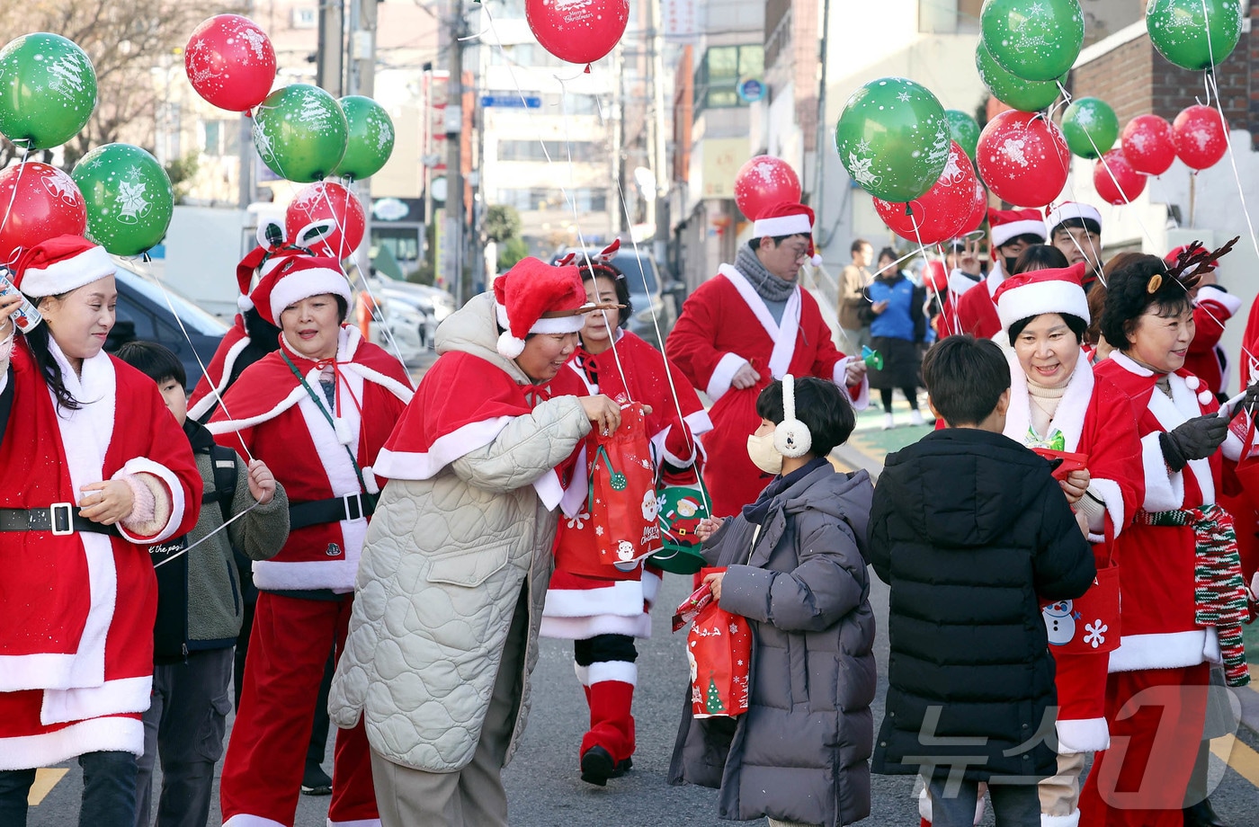 19일 광주 북구 용봉동 용주초등학교 정문 인근에서 산타복장을 하고 몰래산타로 변신한 지역사회보장협의체 회원들과 동행정복지센터 직원들이 크리스마스를 앞두고 하교하는 학생들에게 깜짝 선물꾸러미를 나눠주고 있다.&#40;광주 북구 제공&#41;2024.12.19/뉴스1