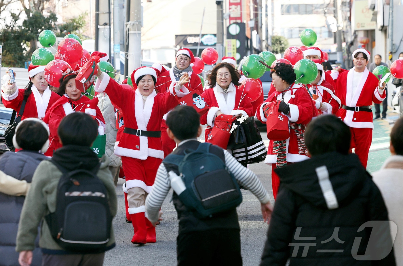 광주 북구 용봉동 용주초등학교 정문 인근에서 산타복장을 하고 몰래산타로 변신한 지역 단체와 공무원들이 하교하는 학생들에게 깜짝 선물꾸러미를 나눠주고 있다.&#40;광주 북구 제공&#41;2024.12.19/뉴스1 ⓒ News1 박지현 기자