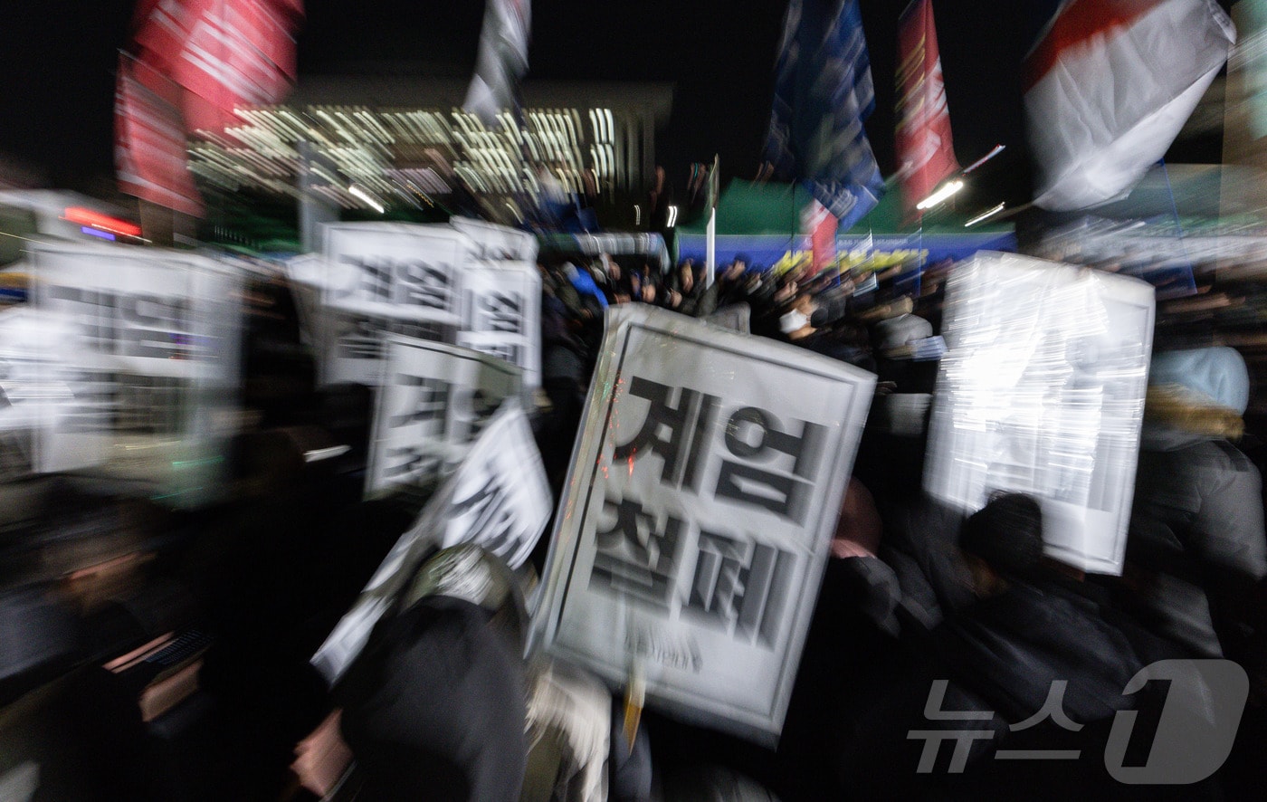 윤석열 대통령의 비상계엄 해제 요구 결의안이 국회 본회의에서 통과된 4일 새벽 서울 여의도 국회 정문 앞에 모인 시민들이 모여 있다. 여야는 이날 본회의에서 재석 190명 중 찬성 190명으로 비상계엄 해제 요구 결의안을 가결 처리했다. 이에 따라 계엄령 선포는 무효가 됐다고 국회의장실은 설명했다. 2024.12.4/뉴스1 ⓒ News1 이재명 기자