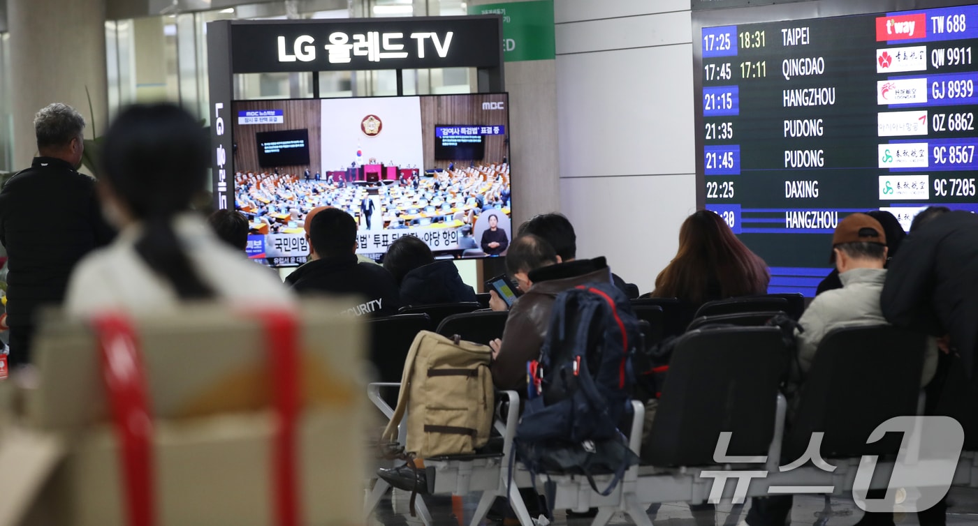 7일 오후 제주국제공항 대합실에서 관광객들이 윤석열 대통령 탄핵소추안 표결과 김건희 특검법 재의결 국회 본회의 TV 생중계를 시청하고 있다. 2024.12.7/뉴스1 ⓒ News1 오현지 기자