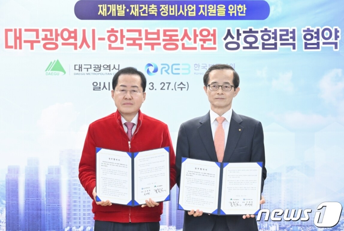 27일 홍준표 대구시장(왼쪽)과 손태락 한국부동산원장이 재개발·재건축 정비사업 지원을 위한 업무협약을 체결한 뒤 협약서를 펼쳐 보이고 있다.(한국부동산원 제공)