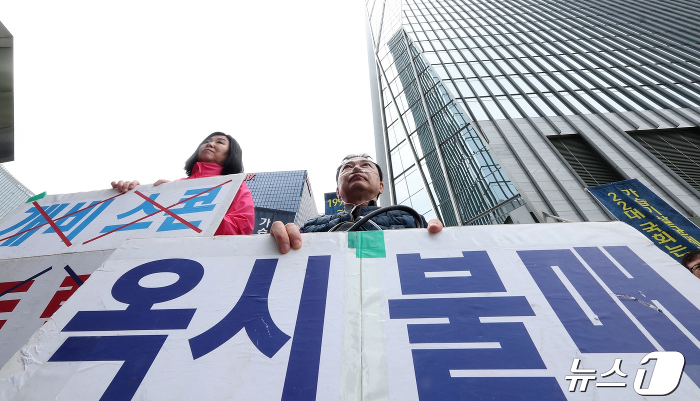 가습기 살균제 참사 피해자 민수연 씨와 서영철 씨가 22일 서울 영등포구 여의도 옥시 사옥 앞에서 열린 '1853번째 가습기살균제 참사 피해자의 죽음' 기자회견에서 손피켓을 들고 자리하고 있다. 2024.4.22 ⓒ 뉴스1 김성진 기자