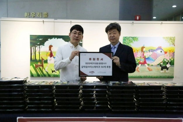 26일 한우리정보문화센터 한우리홀에서 손정호 아웃백 양재점 점주(왼쪽)가 '서초한우리오케스트라' 단원에게 도시락 세트를 전달한 뒤 이재용 서초구립 한우리정보문화센터 관장과 기념사진을 촬영하고 있다.(bhc그룹 제공)