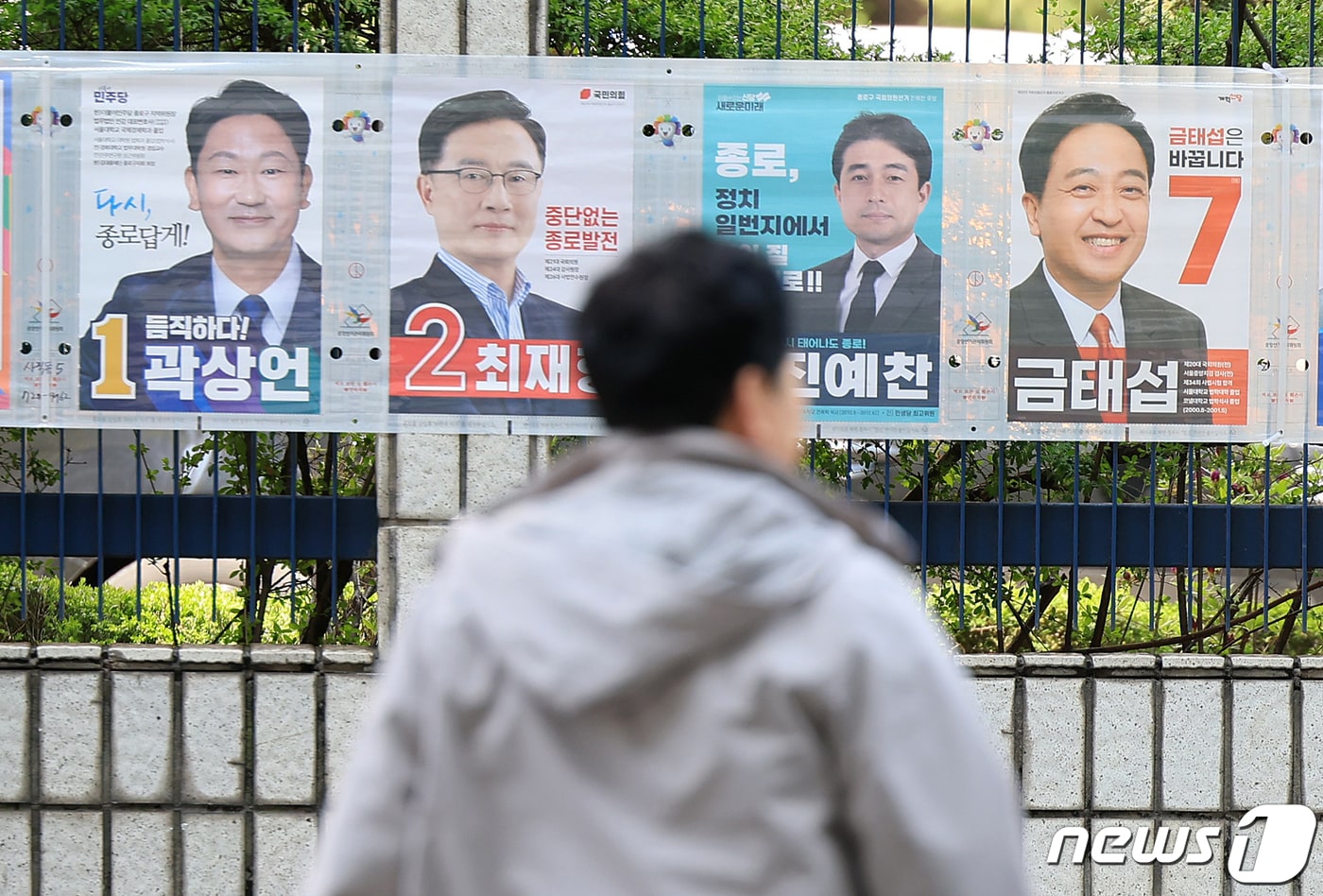 제22대 국회의원 선거를 하루 앞둔 9일 오후 서울 종로구 서울경찰청 앞에서 유권자들이 종로구 후보자들의 선거벽보 앞으로 지나고 있다. 2024.4.9/뉴스1 ⓒ News1 김진환 기자