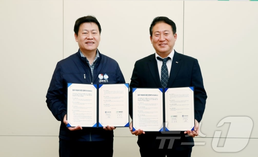 손대권 iM뱅크 개인고객그룹 상무(왼쪽)와 이청암 이디야커피 상무가 역외지역 개인 마케팅 활성화를 위한 업무 협약을 체결한 뒤 협약서를 펼쳐 보이고 있다.(iM뱅크 제공)