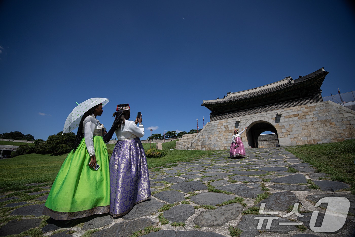 7일 경기도는 무더위가 계속되는 가운데 일부지역에는 새벽시간 최대 20㎜의 소나기가 내릴 것으로 예상된다. 8월28일 오후 수원시 팔달구 세계문화유산 수원화성 창룡문을 찾은 외국인 관광객들이 파란 하늘을 배경으로 기념 촬영을 하고 있다. 2024.8.28/뉴스1 ⓒ News1 이재명 기자