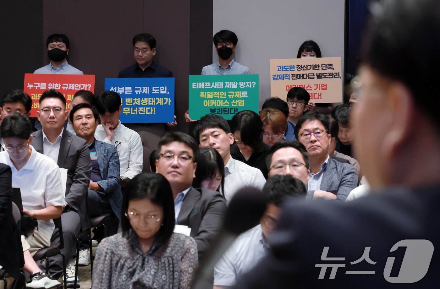 23일 오후 서울 중구 세종대로 한국프레스센터 국제회의장에서 열린 티몬·위메프 사태 재발 방지를 위한 대규모유통업법·전자금융거래법 개정(안) 공청회장 뒤편에서 벤처 협회 관계자들이 정산기한 단축과 판매대금 별도관리안에 대한 반대 입장이 담긴 손피켓을 들고 있다. 2024.9.23/뉴스1 ⓒ News1 박정호 기자