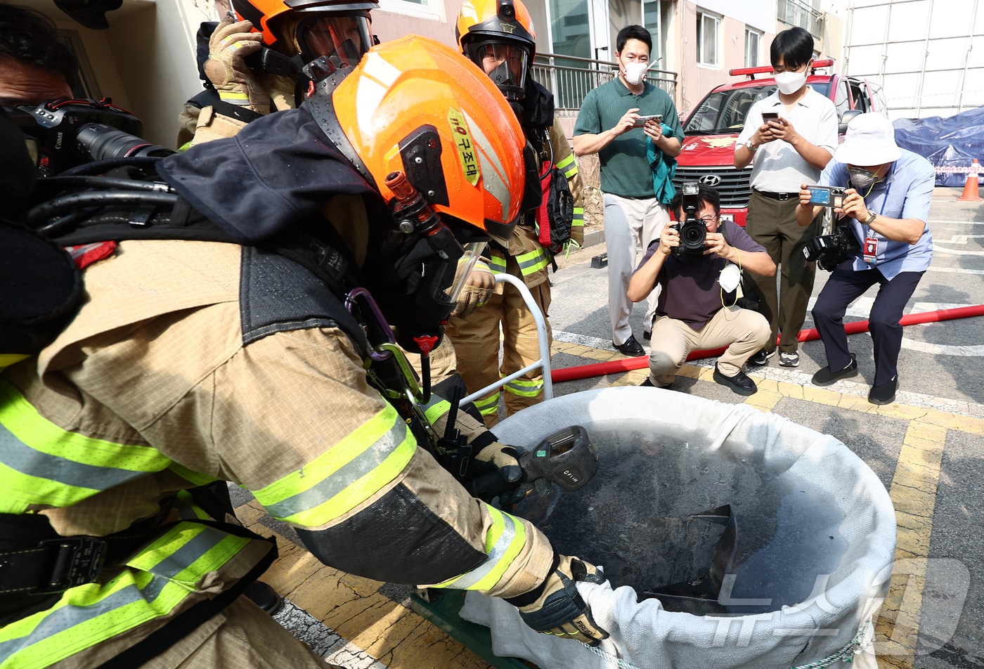 지난 1일 서울 노원구 상계마들아파트에서 열린 '2025 아파트 실험화재 재현실험'에서 서울소방재난본부 소방대원들이 아파트 실내에서 발화를 유도한 리튬이온배터리를 회수해 임시소화수조에 담아 냉각 및 방전시키는 작업을 하고 있다. 2025.10.2/뉴스1 ⓒ News1 김민지 기자