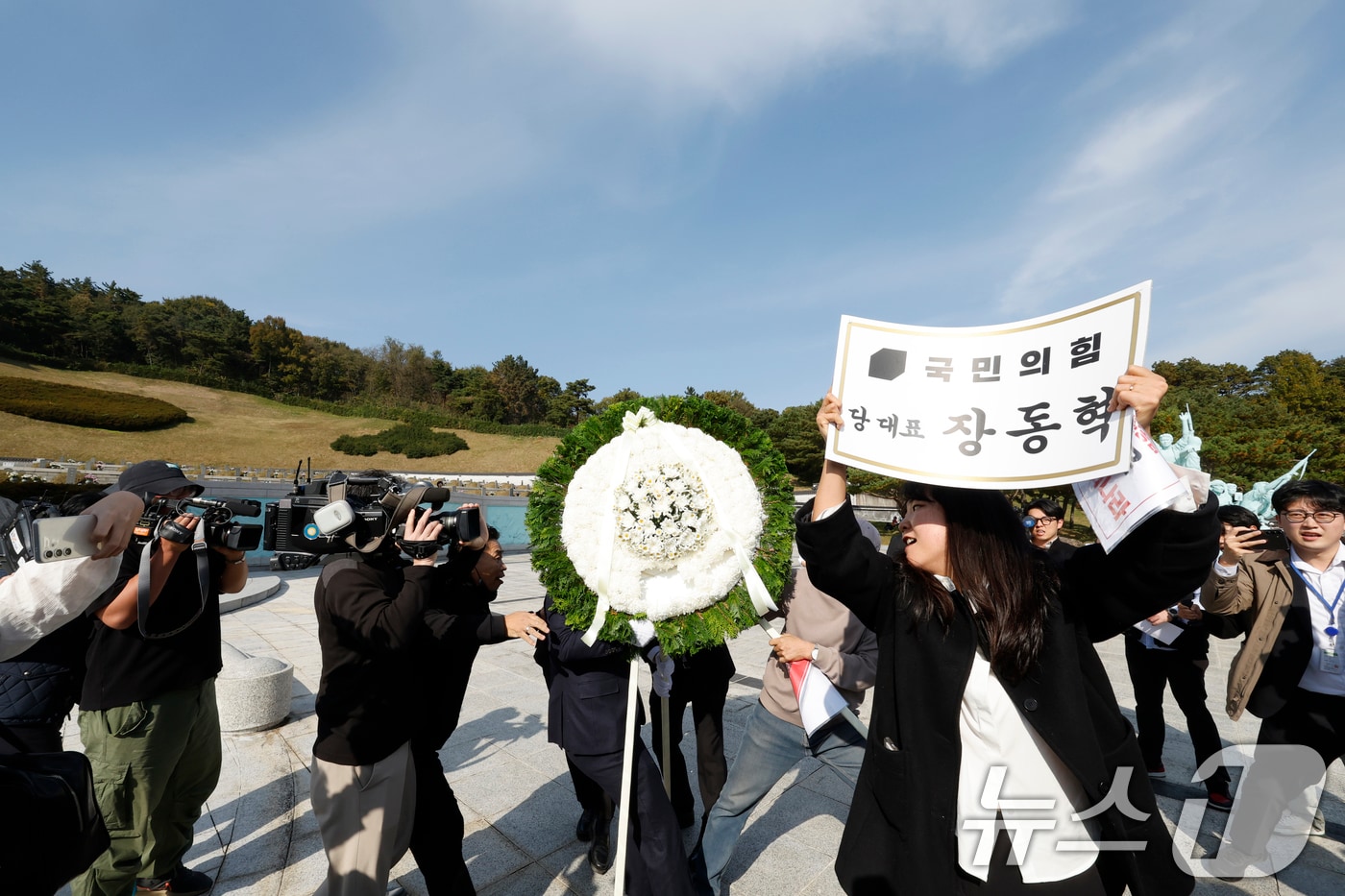 장동혁 국민의힘 대표가 6일 광주를 찾아 국립 5·18민주묘지를 참배하기 위해 들어서자 광주전남촛불행동 회원들이 당대표 조화을 치우고 있다. 2025.11.6/뉴스1 ⓒ News1 김태성 기자