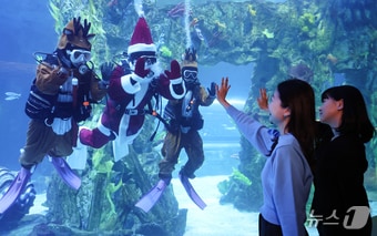 지난 16일 서울 송파구 롯데월드 아쿠아리움 메인수조에서 산타와 루돌프 복장을 한 아쿠아리스트들 방문객을 향해 인사하고 있다. 2025.12.16/뉴스1 ⓒ News1 김도우 기자