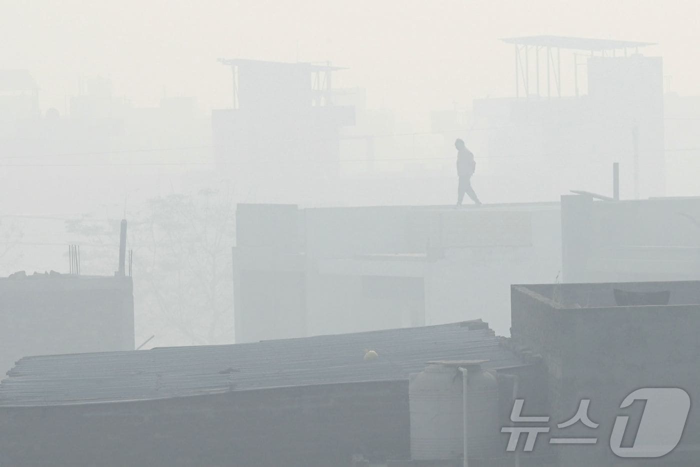 12일 인도 암리차르에서 한 남성이 스모그 속 공장 지붕 위를 걷고 있다.2025.12.12. ⓒ AFP=뉴스1