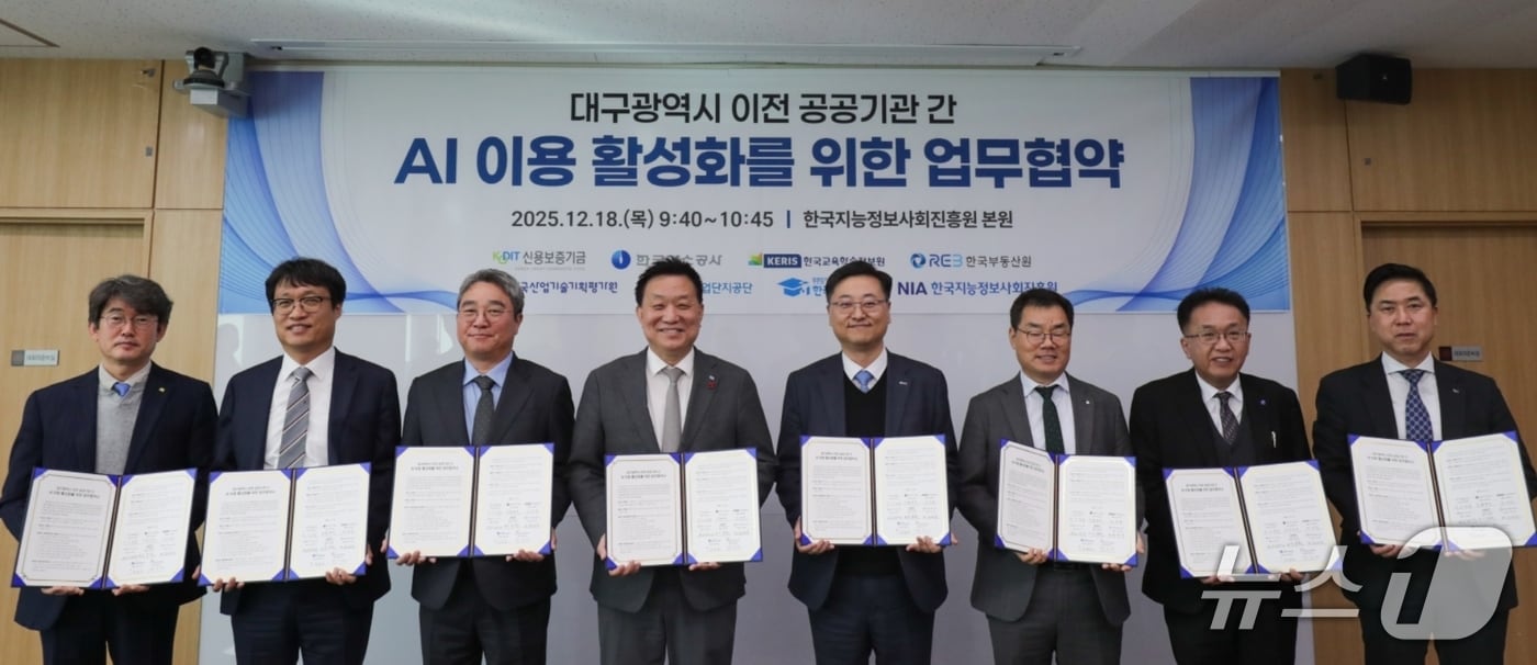 한국지능정보사회진흥원 대구 본원에서 열린 '인공지능(AI) 이용 활성화' 업무협약식에 참석한 신용보증기금과 대구 이전 공공기관 관계자들이 협약서를 펼쳐 보이고 있다.(신보 제공, 재판매 및 DB 금지)