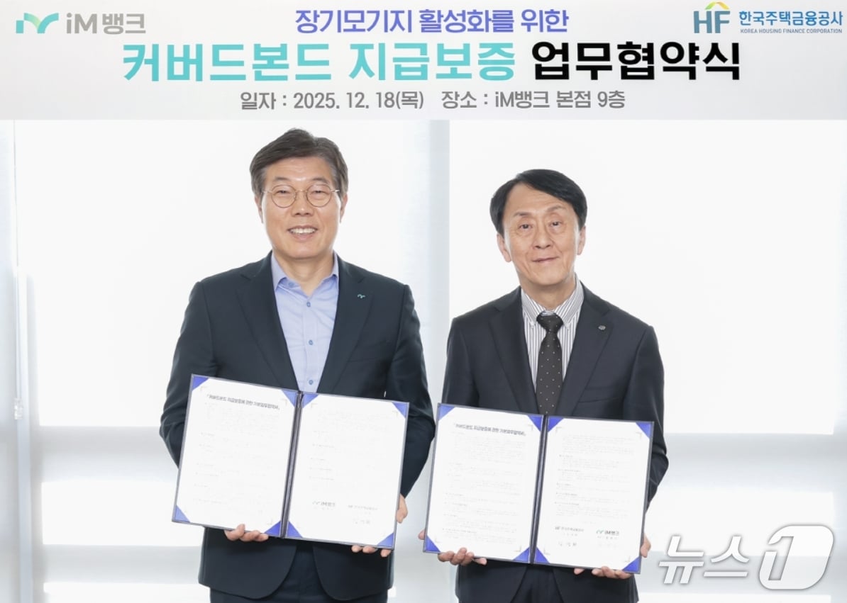 황병우 iM뱅크 은행장(왼쪽)과 김경환 한국주택금융공사 사장이 커버드본드 지급보증 업무협약을 체결한 뒤 협약서를 펼쳐 보이고 있다.(iM뱅크 제공, 재판매 및 DB 금지)