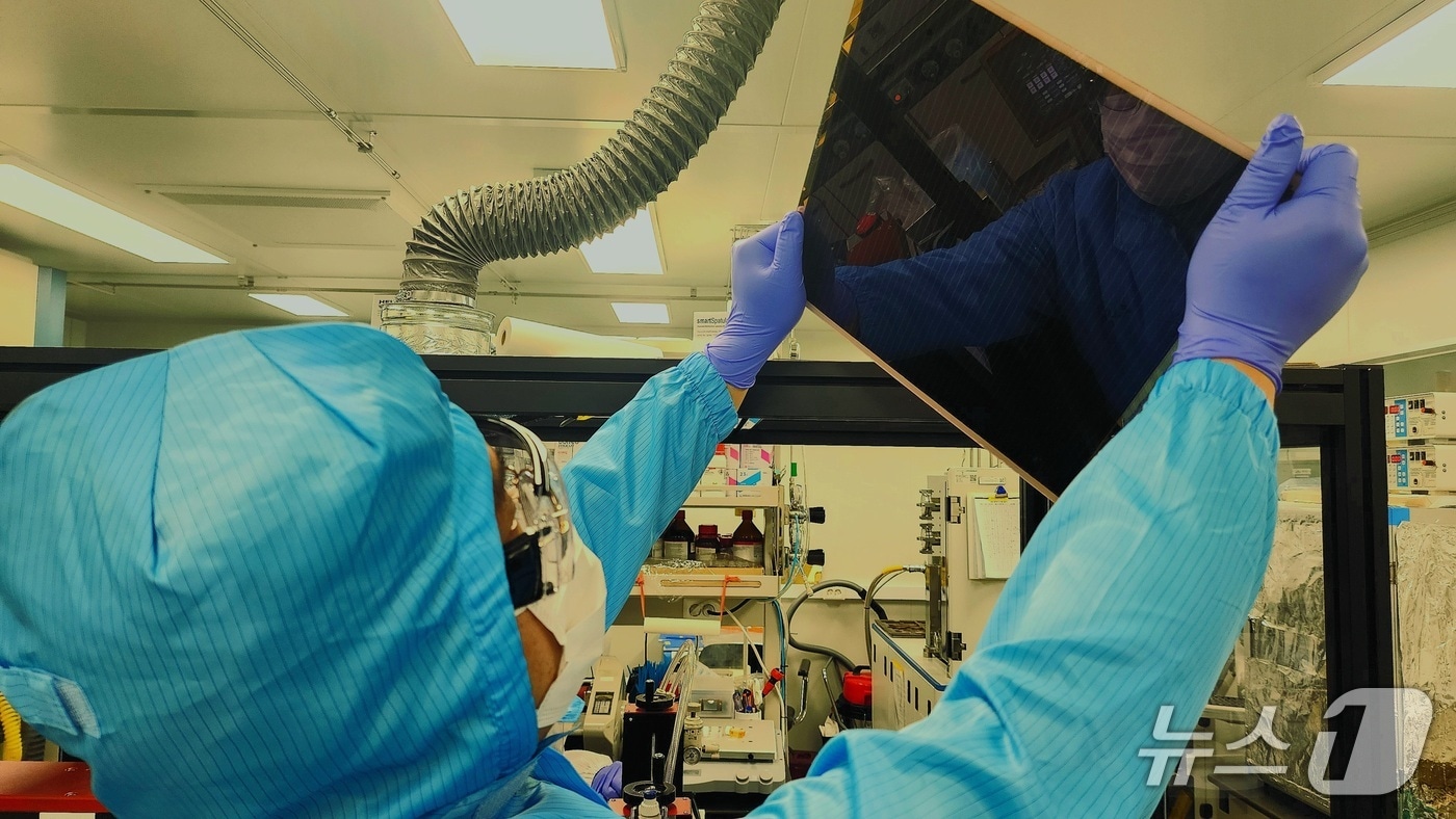 대면적 페로브스카이트 태양전지 기판을 보고있는 엘케이켐 연구원(화학연 제공) /뉴스1