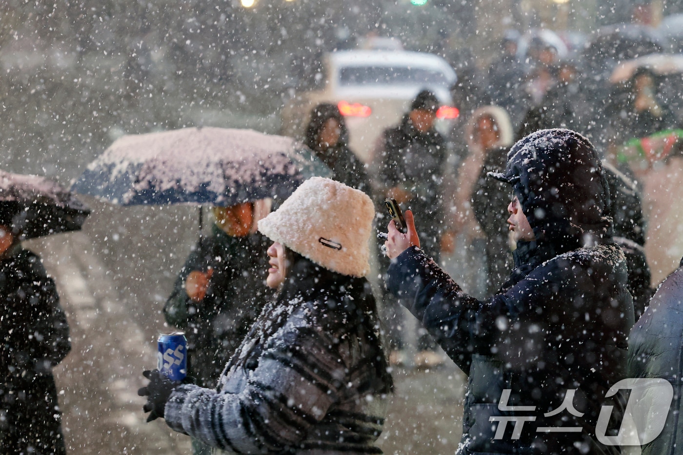 첫눈이 내린 4일 오후 서울 중구 명동을 찾은 관광객들이 내리는 눈을 맞으며 즐거운 시간을 보내고 있다. 기상청은 "퇴근 시간대 강한 눈이 내릴 가능성이 크다"며 동네 예보와 실시간 날씨를 확인할 것을 당부했다. 2025.12.4/뉴스1 ⓒ News1 박정호 기자