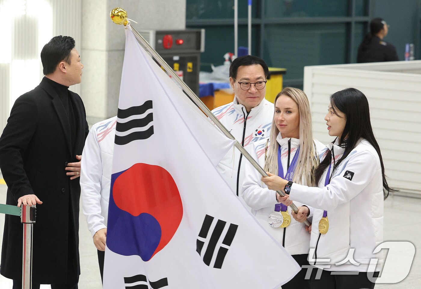 귀화 선수로서 한국 바이애슬론 사상 첫 동계아시안게임 금메달을 획득한 예카테리나 압바꾸모바&#40;왼쪽&#41;와 여자컬링에서 금메달을 차지한 김민지가 15일 오후 인천국제공항 1터미널 귀국장에서 열린 2025 하얼빈 동계 아시안게임 한국 선수단 귀국 환영 행사에 태극기를 들고 입장하고 있다. 8년 만에 열린 이번 대회에 한국은 총 222명의 선수단을 파견해 금메달 16개, 은메달 15개, 동메달 14개를 수확하며 개최국 중국&#40;금 32·은 27·동 25&#41;에 이어 종합 2위를 차지했다. 2025.2.15/뉴스1 ⓒ News1 신웅수 기자
