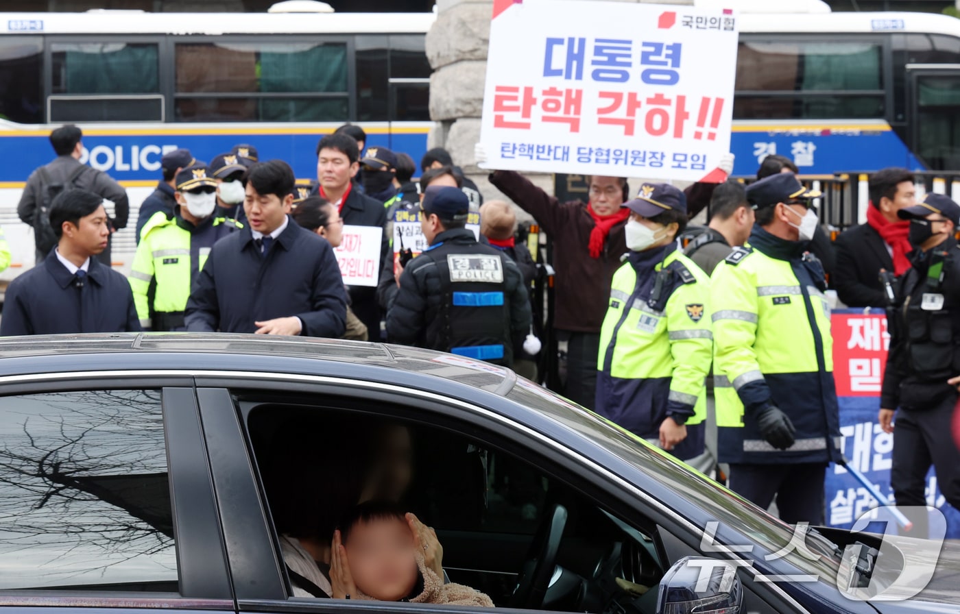 12일 서울 종로구 헌법재판소 앞에서 차량으로 이동하는 시민이 욕설하는 시위대로 부터 아이의 귀를 가리고 있다. 2025.3.12/뉴스1 ⓒ News1 김명섭 기자