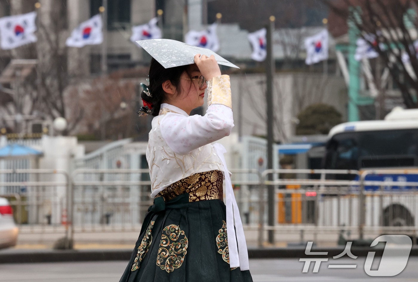 비가 내리는 2일 서울 경복궁 앞에서 한복을 입은 한 시민이 우산대신 프린트물로 비를 피하고 있다.2025.3.2/뉴스1 ⓒ News1 박세연 기자