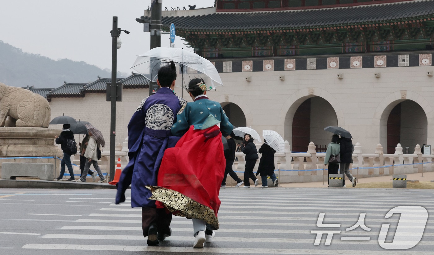 서울 경복궁 앞에서 한복을 입고 우산을 쓴 관광객이 발걸음을 재촉하고 있다.2025.3.2/뉴스1 ⓒ News1 박세연 기자