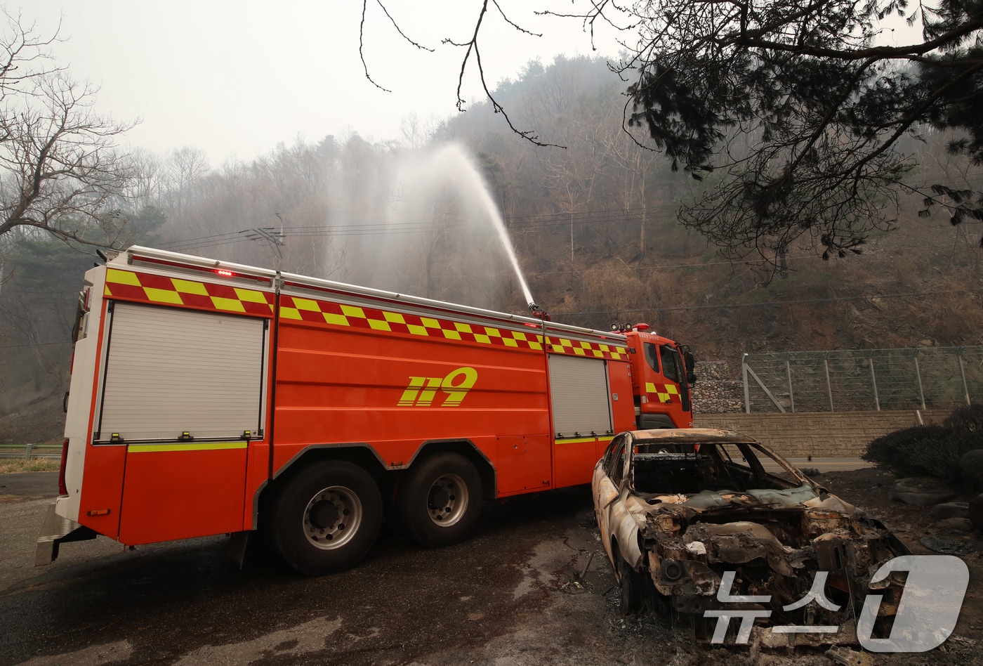 경남 산청 대형 산불이 사흘째로 접어든 23일 오전 산청군 시천면 일대에서 소방이 산불로 인해 전소된 승용차 뒤로 잔불을 정리하고 있다. 2025.3.23/뉴스1 ⓒ News1 윤일지 기자