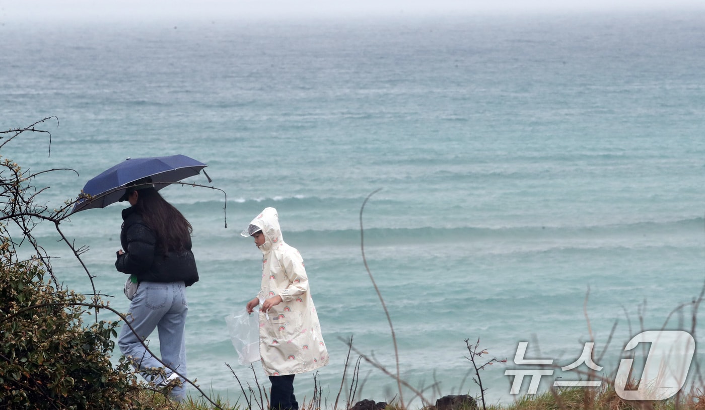 비가 내리는 27일 오후 제주시 조천읍 함덕해수욕장에서 우산을 쓴 관광객들이 이동하고 있다. 2025.3.27/뉴스1 ⓒ News1 오현지 기자
