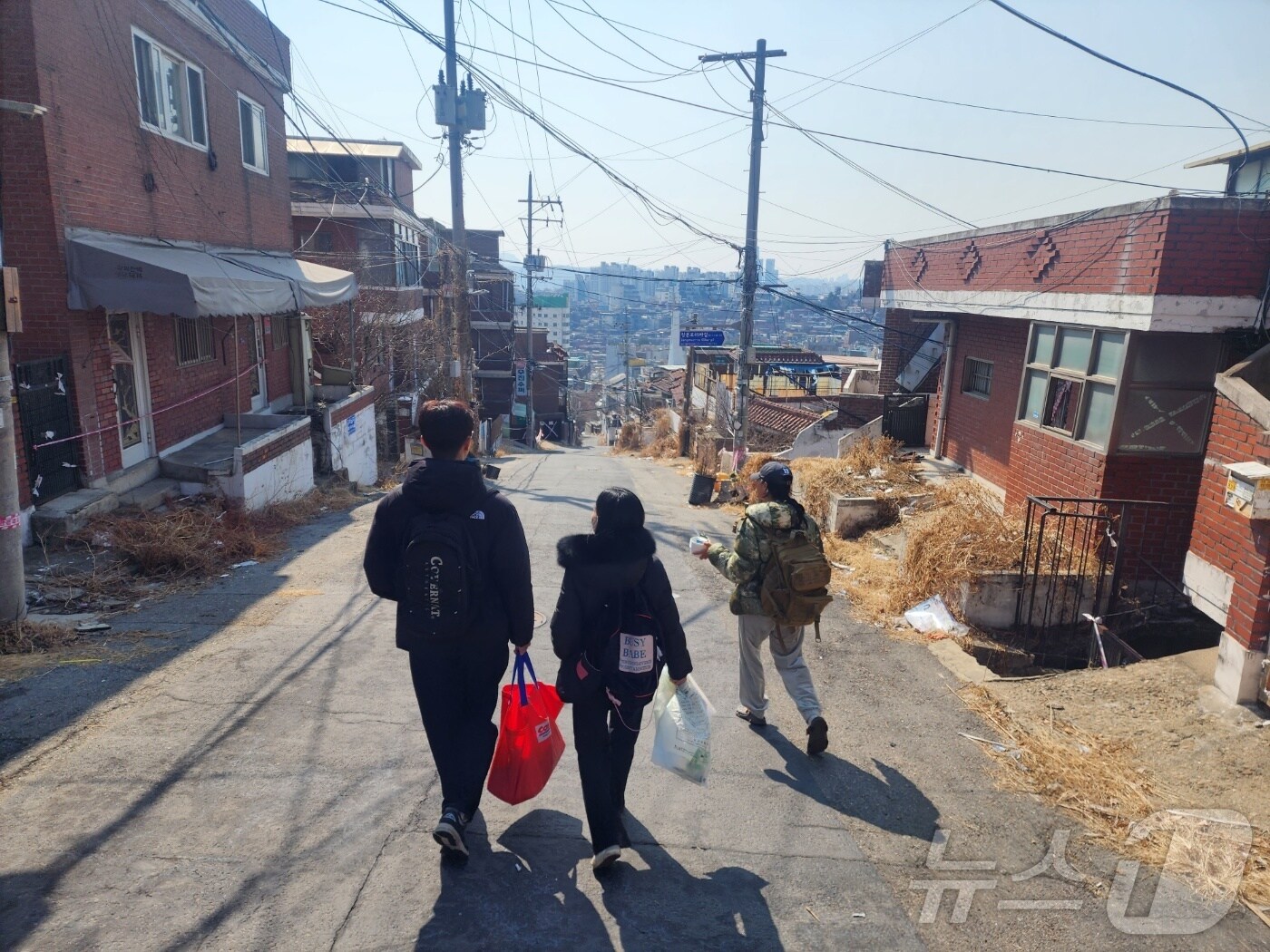 8일 서울시 용산구 내 재개발지 한남 3구역에서 김유진 케어테이커(맨 오른쪽)와 일일 자원봉사자들이 고양이 배식 봉사를 위해 언덕을 내려가고 있다. 2025.03.08/ⓒ 뉴스1ⓒ 뉴스1 권진영 기자