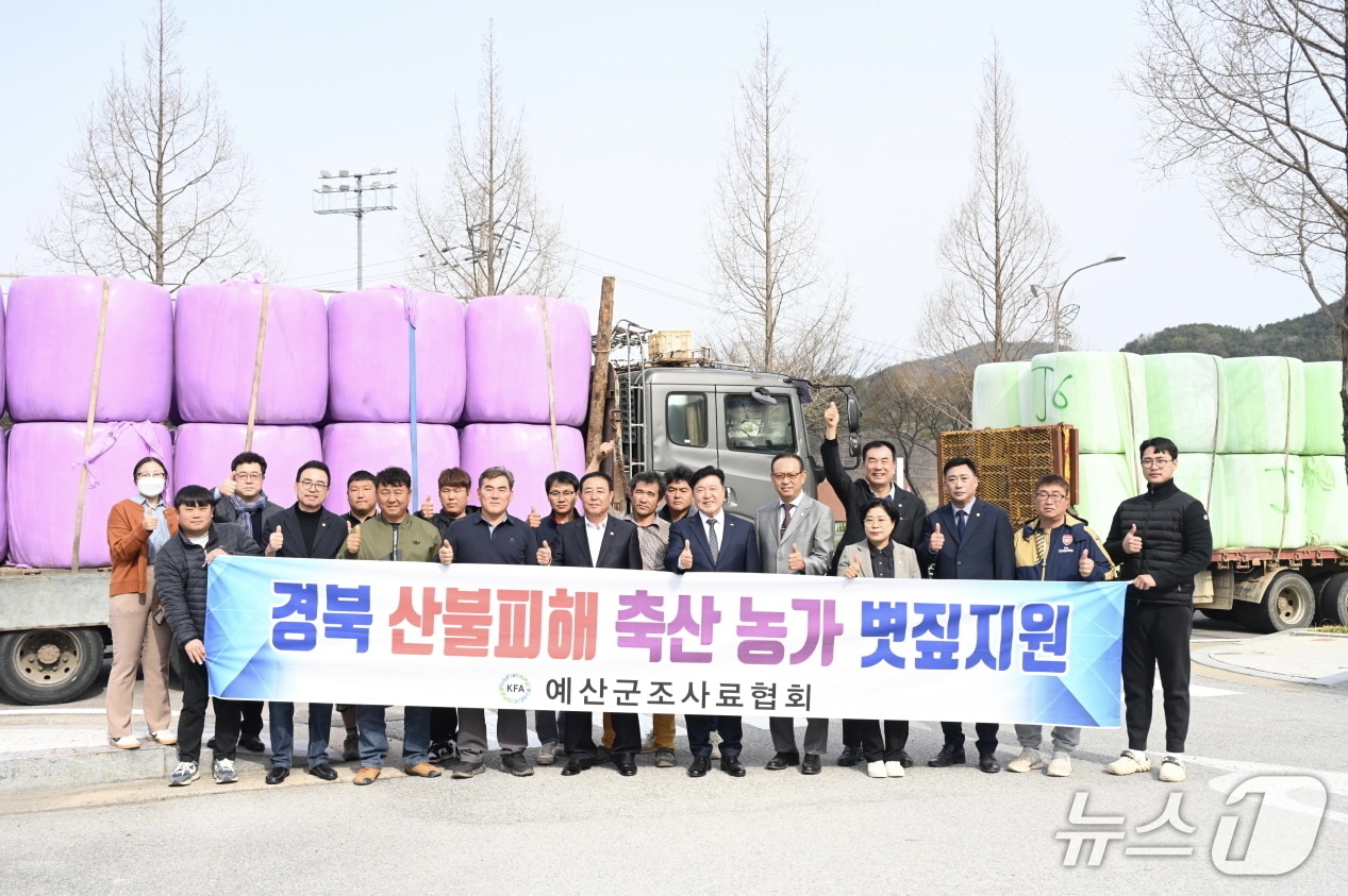 예산 조사료협회  등 관계자들이 경북 산불 피해 축산농가 지원 볏짚 앞에서 기념촬영을 하고 있다. (예산군 제공. 재판매 및 DB금지)/뉴스1