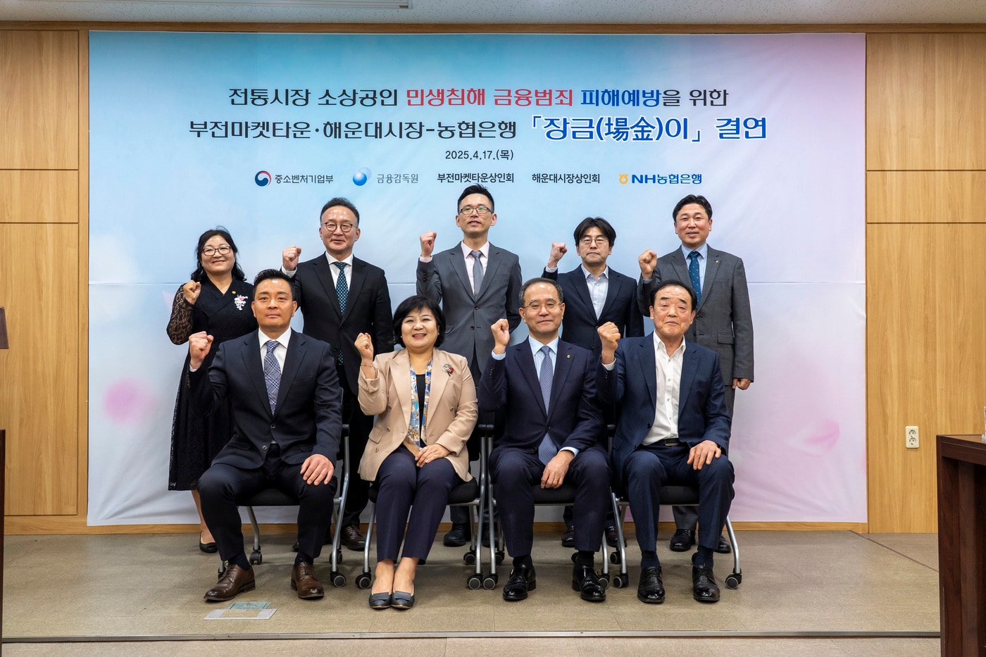 지난 17일 NH농협은행 부산본부에서 김미영 금융감독원 금융소비자보호처장(앞줄 왼쪽 두 번째), 강기성 부산지방중소벤처기업청장(뒷줄 왼쪽 세 번째), 이찬우 NH농협금융지주 회장(앞줄 왼쪽 세 번째), 최동원 부전마켓타운 상인회장(앞줄 왼쪽 네 번째), 장영국 해운대시장 상인회장(앞줄 왼쪽 첫 번째) 등 주요관계자들이 참석하여 ‘장금이결연’ 기념촬영을 하고 있다. (NH농협은행 제공)