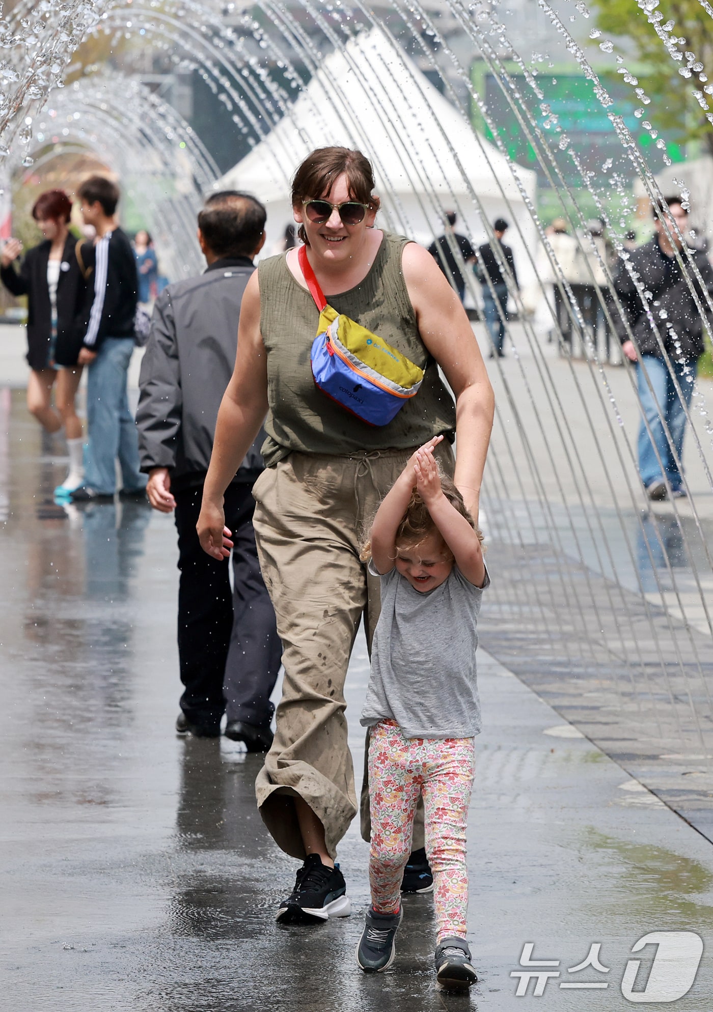 서울의 낮 최고기온이 20도를 기록하는 등 완연한 봄날씨를 보인 18일 오후 서울 종로구 광화문광장을 찾은 외국인 관광객들이 분수 터널을 통과하고 있다. 기상청은 당분간 따뜻하지만, 일교차가 큰 봄 날씨가 이어질 것으로 내다보고 있다. 2025.4.18/뉴스1 ⓒ News1 김진환 기자