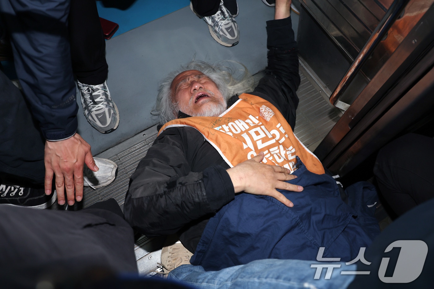 박경석 전국장애인차별철폐연대(전장연) 대표가 21일 서울 지하철 4호선 혜화역 동대문 방면 승강장에서 제62차 '출근길 지하철 탑니다' 시위를 벌이던 중 이를 저지하던 경찰·서울교통공사 직원 등과 충돌하며 열차 입구에 넘어져 있다.  2025.4.21/뉴스1 ⓒ News1 이동해 기자