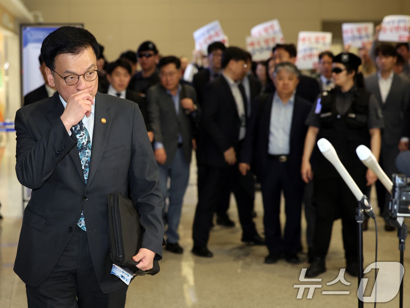 최상목 경제부총리 겸 기획재정부 장관이 22일 오전 인천국제공항에서 한·미 2+2 통상협의(Trade Consultation)와 주요 20개국(G20) 재무장관회의, 국제통화금융위원회(IMFC) 참석을 위해 출국하고 있다. 출국하는 최 부총리 뒤쪽으로 진보당원들이 손팻말을 들고 대미 협상 추진을 규탄하고 있다. 2025.4.22/뉴스1 ⓒ News1 황기선 기자