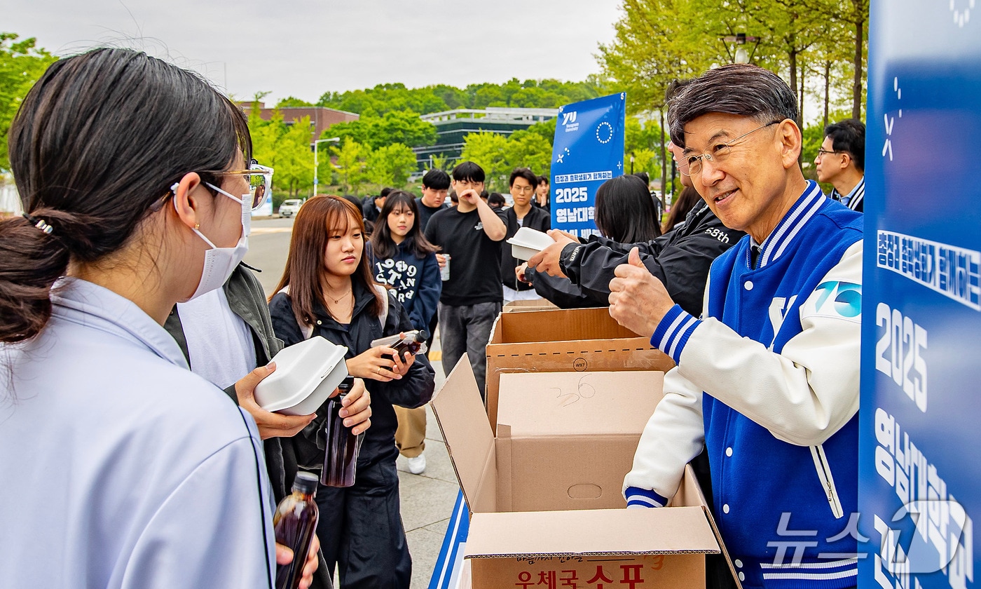 최외출 영남대 총장(오른쪽)이 교내 중앙도서관 앞에서 중간시험을 준비하는 학생들에게 간식을 나눠주며 응원하고 있다. (영남대 제공)