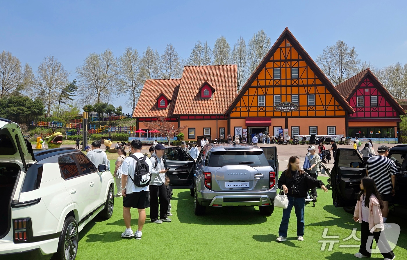 19일 경기 안성의 테마파크 안성팜랜드에 전시된 KG모빌리티 스포츠유틸리티차(SUV) '토레스 하이브리드'를 관람객들이 살펴보는 모습(KG모빌리티 제공). 2025.04.19.